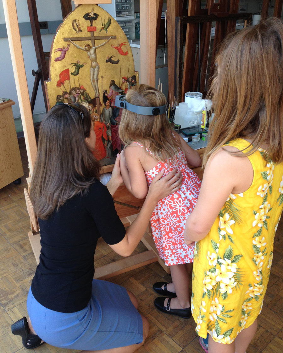 A conservator and two children having a closer look at a painting