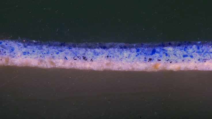Cross section sample taken from blue drapery, with lapis lazuli pigment particles visible in the top paint layers.