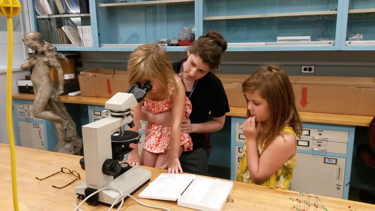 A conservator a two children examining a dispersed pigment sample