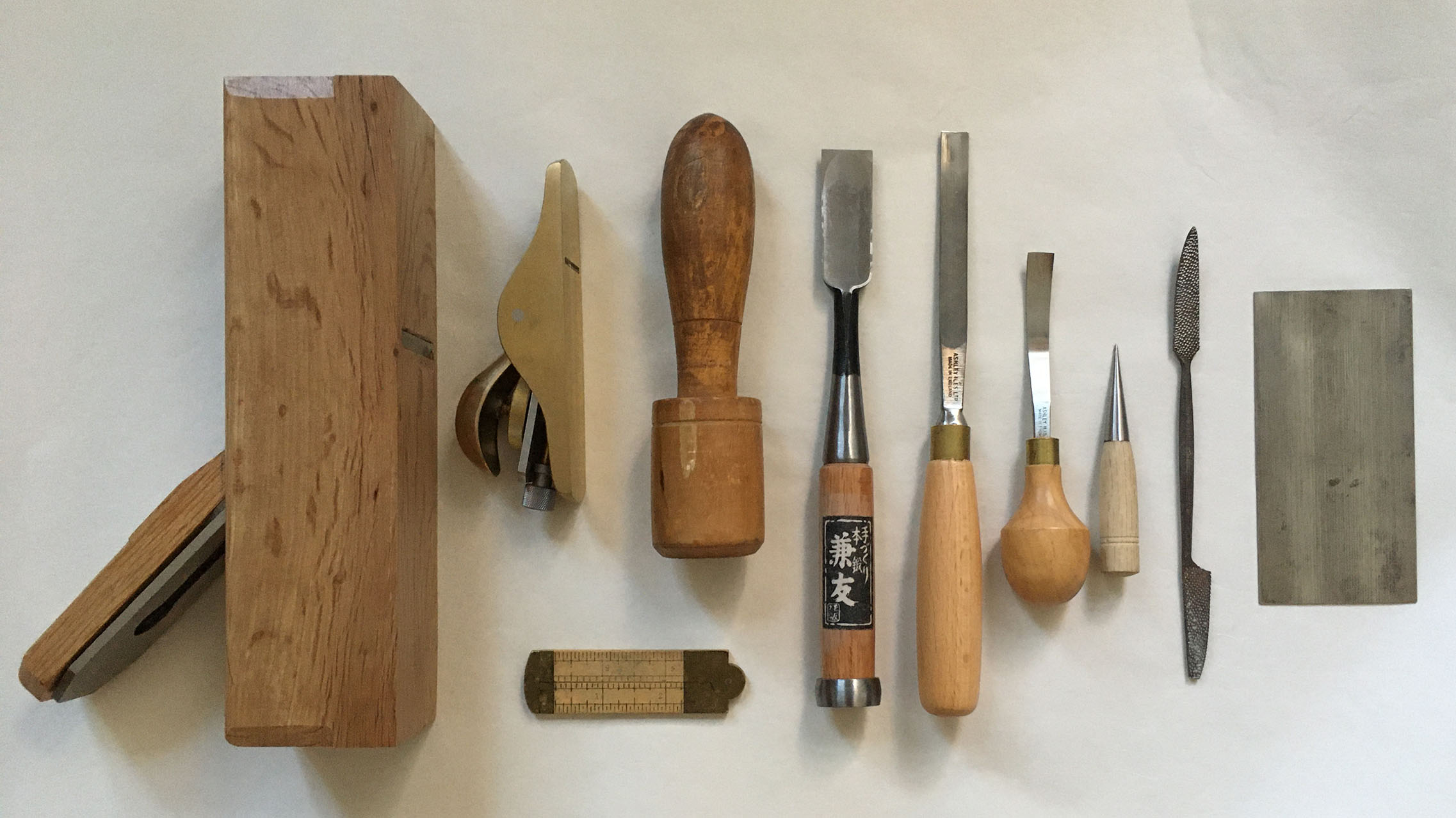 Tools used to shape wood (left to right): block plane, sole plane, ruler, mallet, flat chisel, straight gouge, curved gouge, awl, rasp, and cabinet scraper